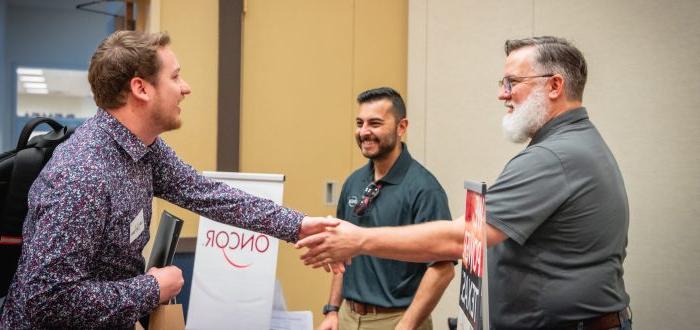 A student shakes hands with potential employers at a career fair.